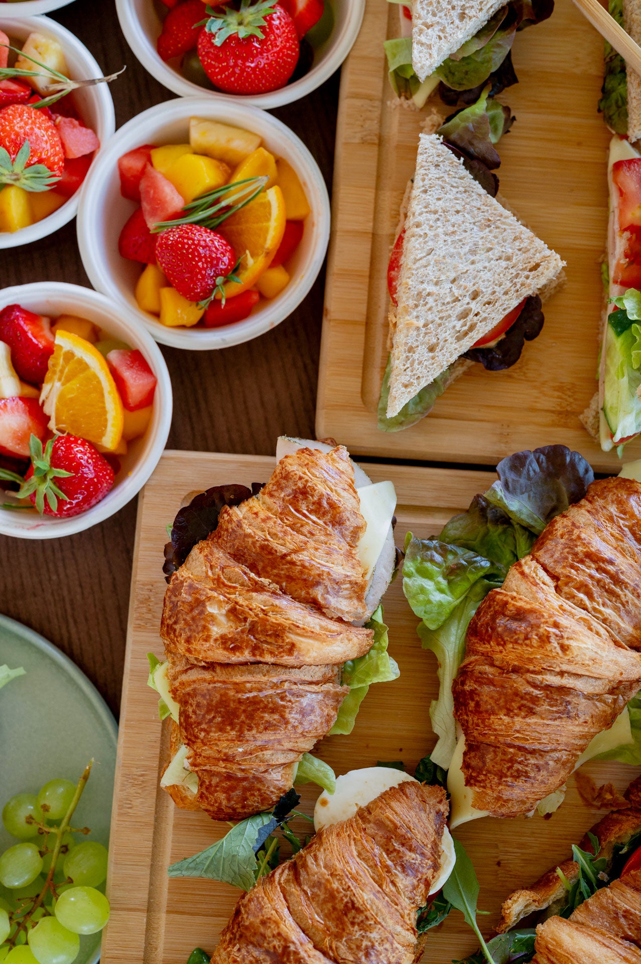 Große Auswahl an Frühstücksboxen mit Croissants, Sandwiches und frischen Obstschalen – liebevoll angerichtet für Teammeetings, Events oder Business-Frühstücke