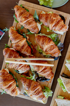 Stuffed French croissants with tomato mozarella and salad, placed on a wooden board.