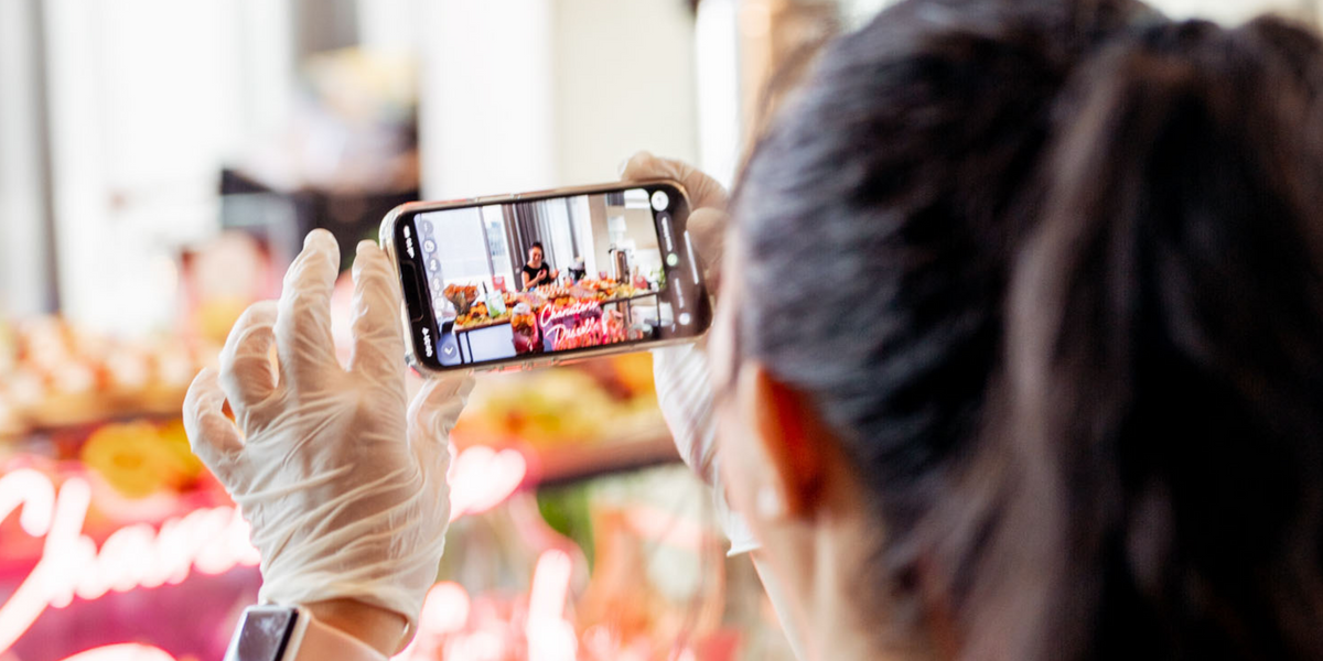 Mädchen hält iPhone und fotografiert unser köstliches Catering-Angebot, das so präsentiert wird, dass es perfekt für Instagram ist.