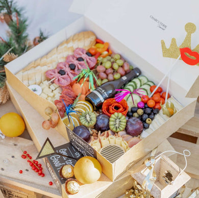 Charcuterie Box with a lot of ingredients like baguette, croissant, pancakes, grapes, cheese, brie, gouda some candies, meat, strawberries, bellpeppers, jam and Hummus. Also some chocolates and decorations. With a bottle of secco from Scavi and Ray